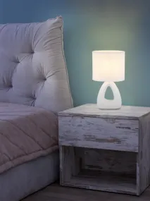 Triangle 30cm Valkoinen pöytävalaisin valmistajalta Globo Lighting - Den triangelformade basen med ett stilrent utskuret h&aring;l ger ett modernt intryck, medan den ovala textilsk&auml;rmen i vit f&auml;rg sprider ett behagligt och j&auml;mnt ljus.