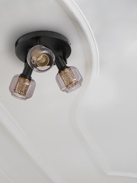 Firefly 3 Musta kohdevalaisin valmistajalta Ledvance - De r&ouml;rliga spotlightsen med sk&auml;rmar av gr&aring;tonat glas i kombination med de guldiga detaljh&ouml;ljet som omfamnar ljusk&auml;llorna bidrar med en elegans till rummet.