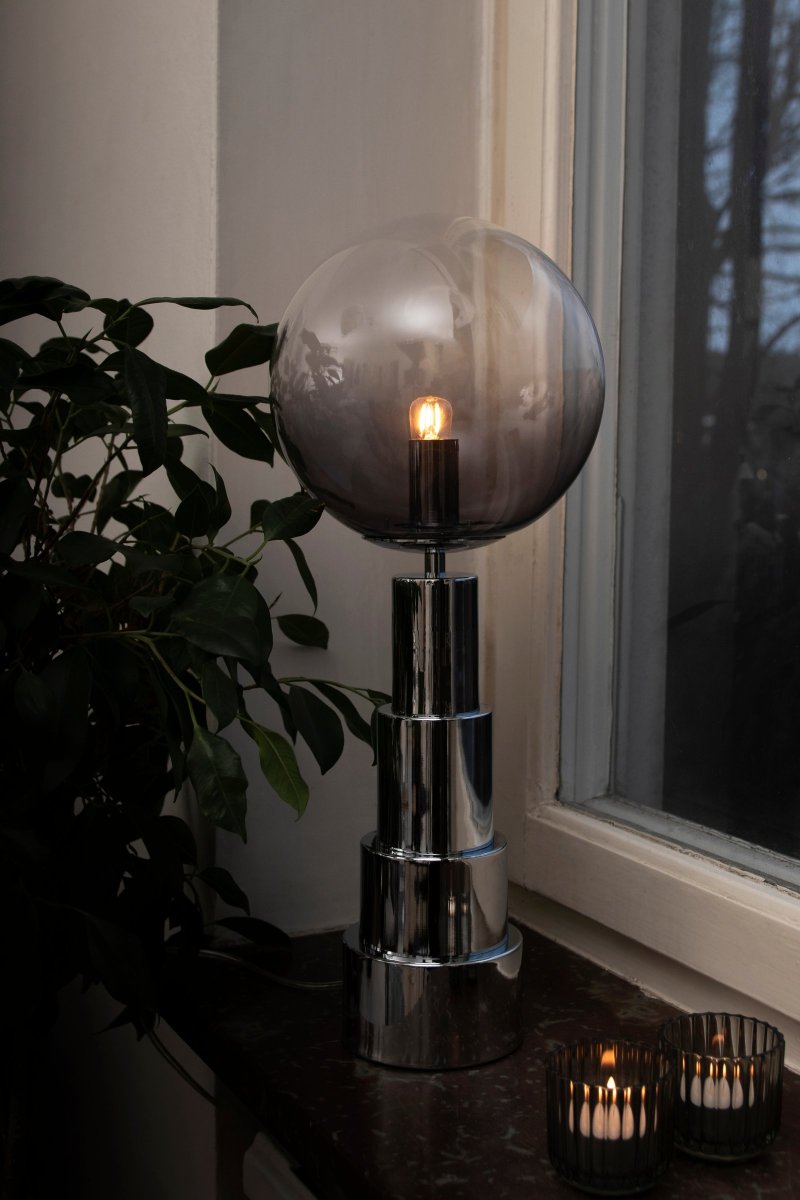 Astro 48cm Kromi pöytävalaisin valmistajalta Globen Lighting - Valaisin on valmistettu krominvärisestä metallista ja siinä on lasipallo, joka on sävytetty savusta kirkkaaksi.