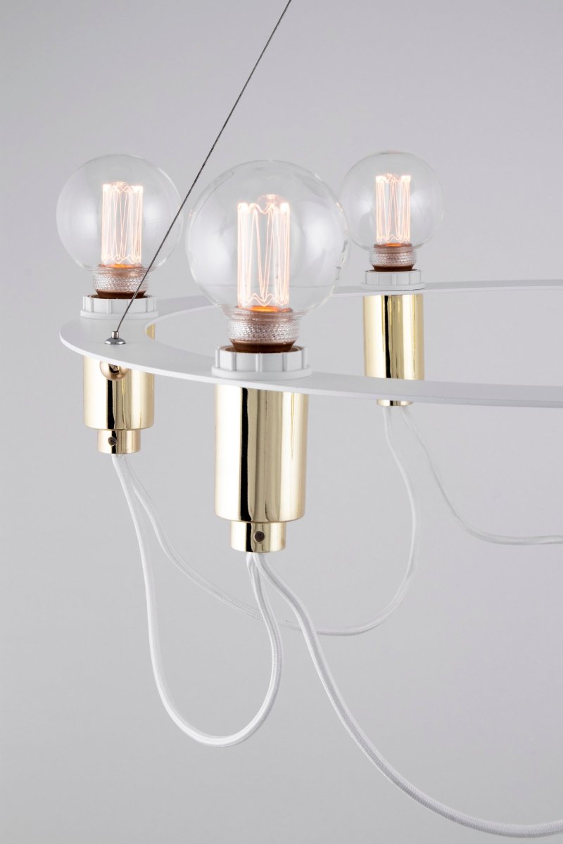 Cables Ø60 Valkoinen kattovalaisin valmistajalta Globen Lighting - Kattokruunu, jossa kiilt&auml;v&auml; messinki, joka roikkuu mattalakatusta py&ouml;re&auml;st&auml; valkoisesta metallirenkaasta.