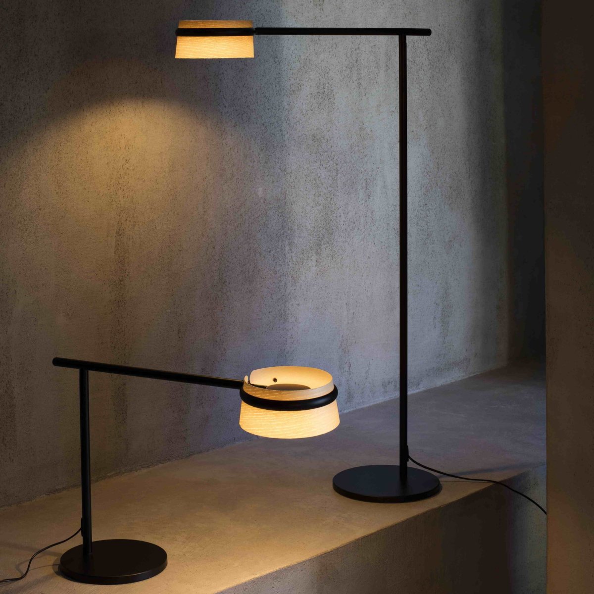 Loop Puu lattiavalaisin valmistajalta Faro Barcelona - Lattiavalaisimelle on ominaista suorakulmainen muoto, py&ouml;re&auml; metallijalka ja elegantti varsi, joka ymp&auml;r&ouml;i saarnipuuvarjostinta.