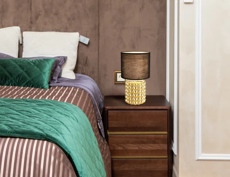 Valentino 33cm Kulta pöytävalaisin valmistajalta Globo Lighting - P&aring; en cylinderformad fot i guldf&auml;rgad keramik vilar en stilren, svart textilsk&auml;rm.