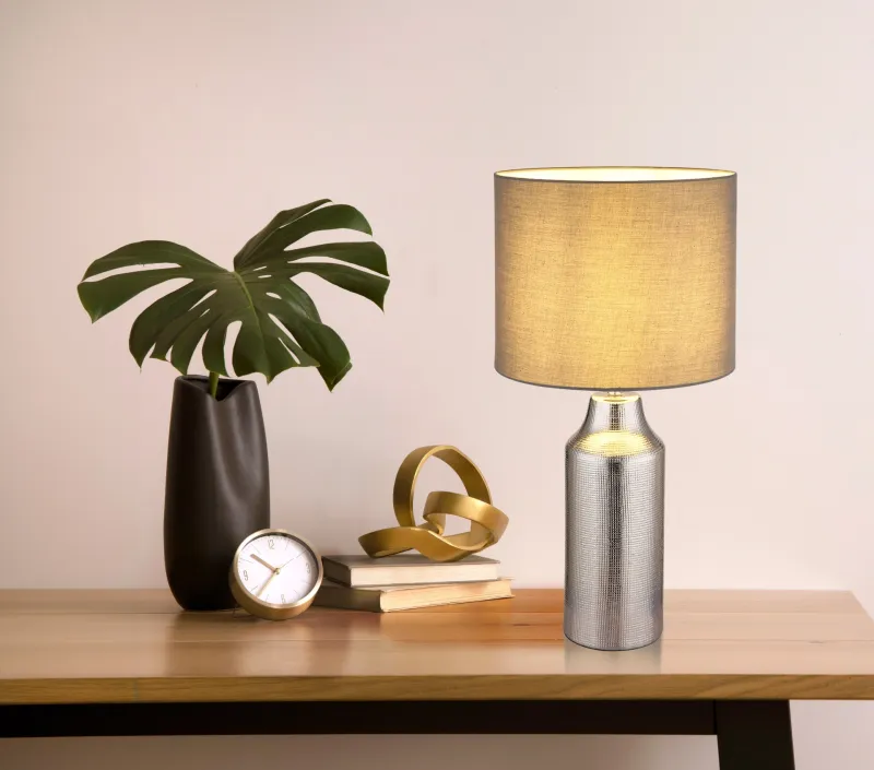 Elden 60cm Hopea pöytävalaisin valmistajalta Globo Lighting - Den silverf&auml;rgade keramiska basen i kombination med den gr&aring;a cylindriska textilsk&auml;rmen skapar en sofistikerad kontrast och blir en stilfull inredningsdetalj.