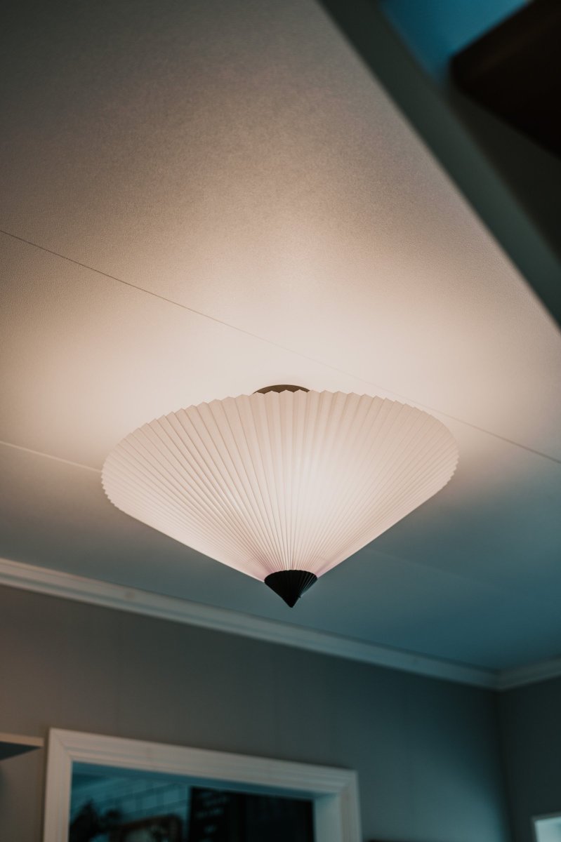 Matisse Ø60 Valkoinen plafondi valmistajalta Globen Lighting - Valaisimessa on laskostettu valkoinen tekstiilivarjostin ja sit&auml; koristaa siihen sopiva laskostettu yl&auml;osa mattamustaksi lakattua metallia.