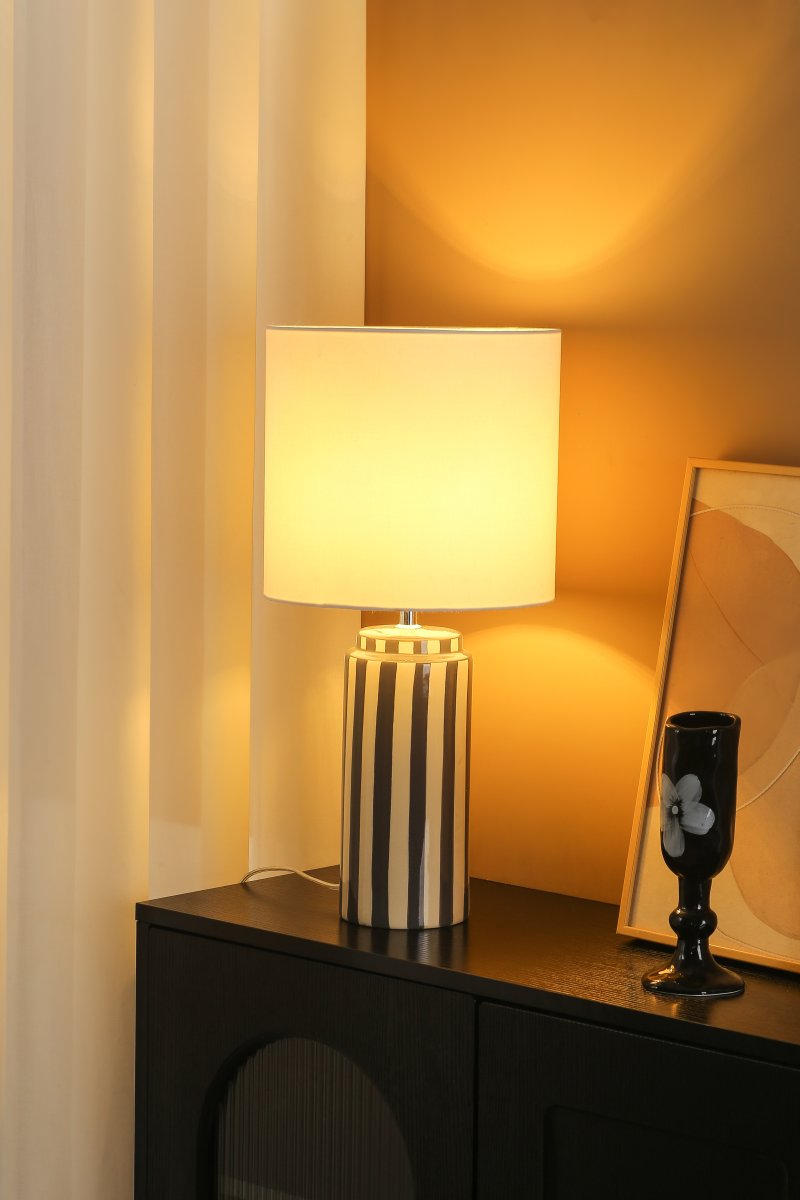 Faro 50cm Harmaa/valkoinen pöytävalaisin valmistajalta Nordic Lighting - Lampun jalka on valmistettu keraamisesta materiaalista, ja sen kermanvalkoinen jalusta ja harmaat raidat luovat eloisan mutta tasapainoisen vaikutelman.