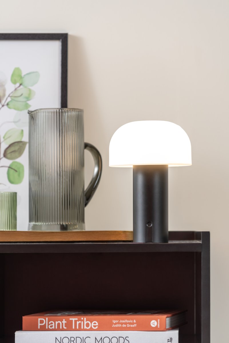 Luca LED 22cm Musta Siirrettävä valmistajalta Leitmotiv - Se on valmistettu metallista, jossa on mattamusta viimeistely, ja siinä on maitomainen valkoinen muovivarjostin, joka levittää pehmeää ja miellyttävää valoa.