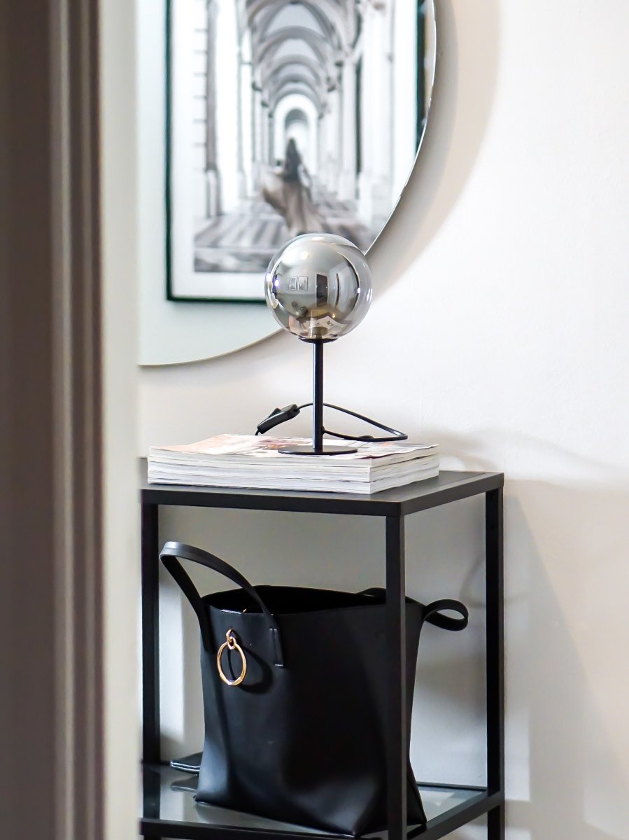 Molekyl 27cm Savun harmaa pöytävalaisin valmistajalta Aneta Lighting - Pienen kokonsa ja savulasivarjostimensa ansiosta se levittää miellyttävää, pehmeää valoa, joka luo kutsuvan tunnelman.